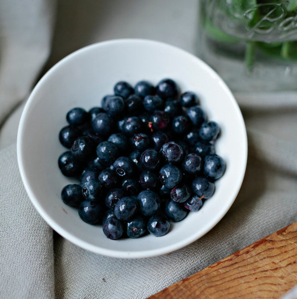 A white bowl filled with freshly washed blueberries