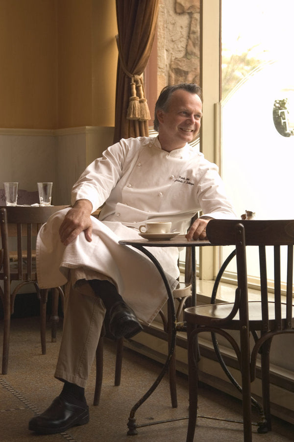 Chef Frank Stitt sitting at a cafe table near a window