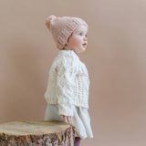 Side view of a child wearing the cream Fisherman Sweater, Stone Hollow Farmstead