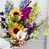 Colorful bouquet of flowers including sunflowers, calla lilies, and various other types.