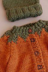 Pumpkin Cardigan knit detail beside a green hat, Stone Hollow Farmstead